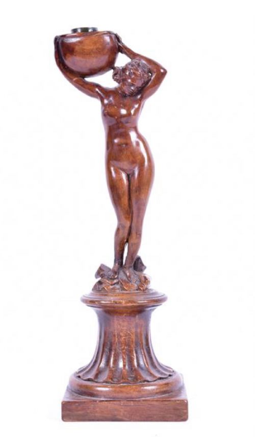 a carved walnut candlestick modelled as a nude woman