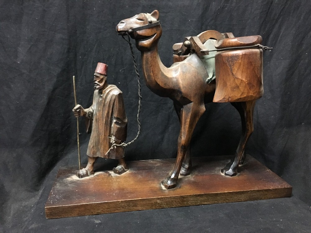 carved wooden man leading a camel