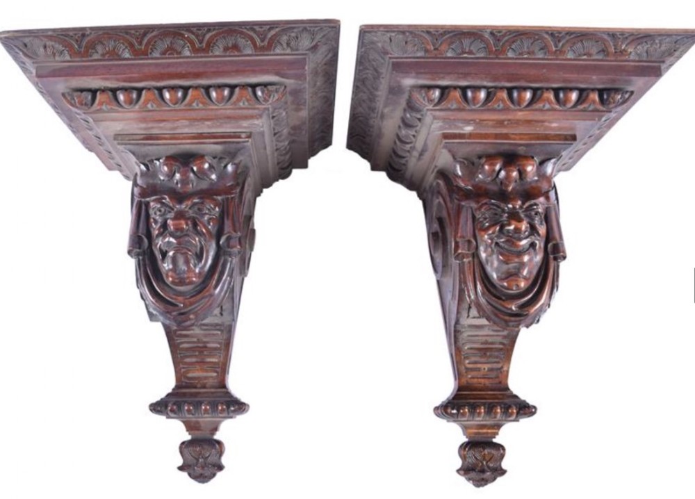 a pair of carved walnut commedia del'arte wall brackets