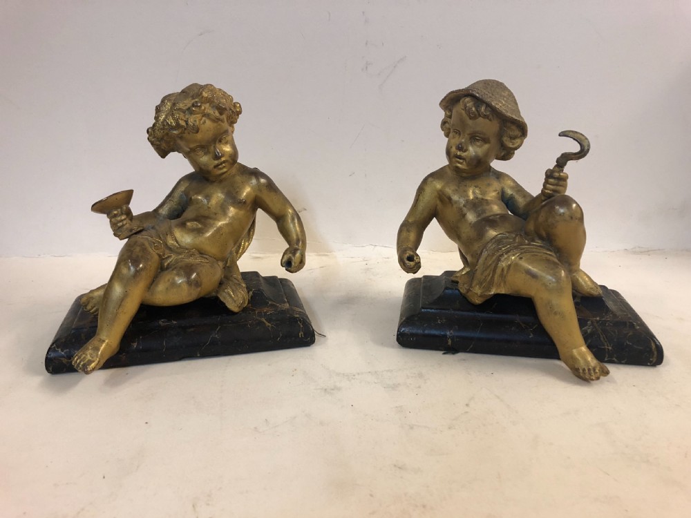 pair of gilt metal cherub ornaments on marble bases