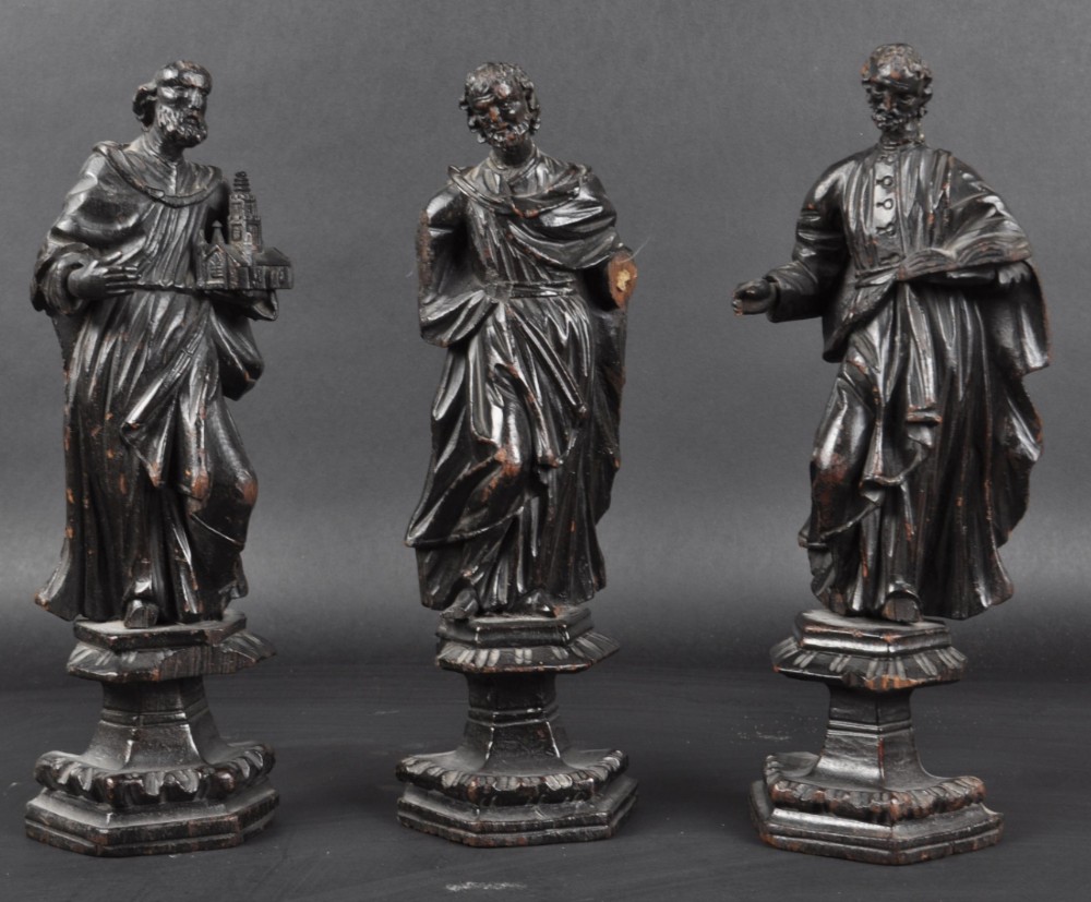a group of three c17th carved wood saints on stands