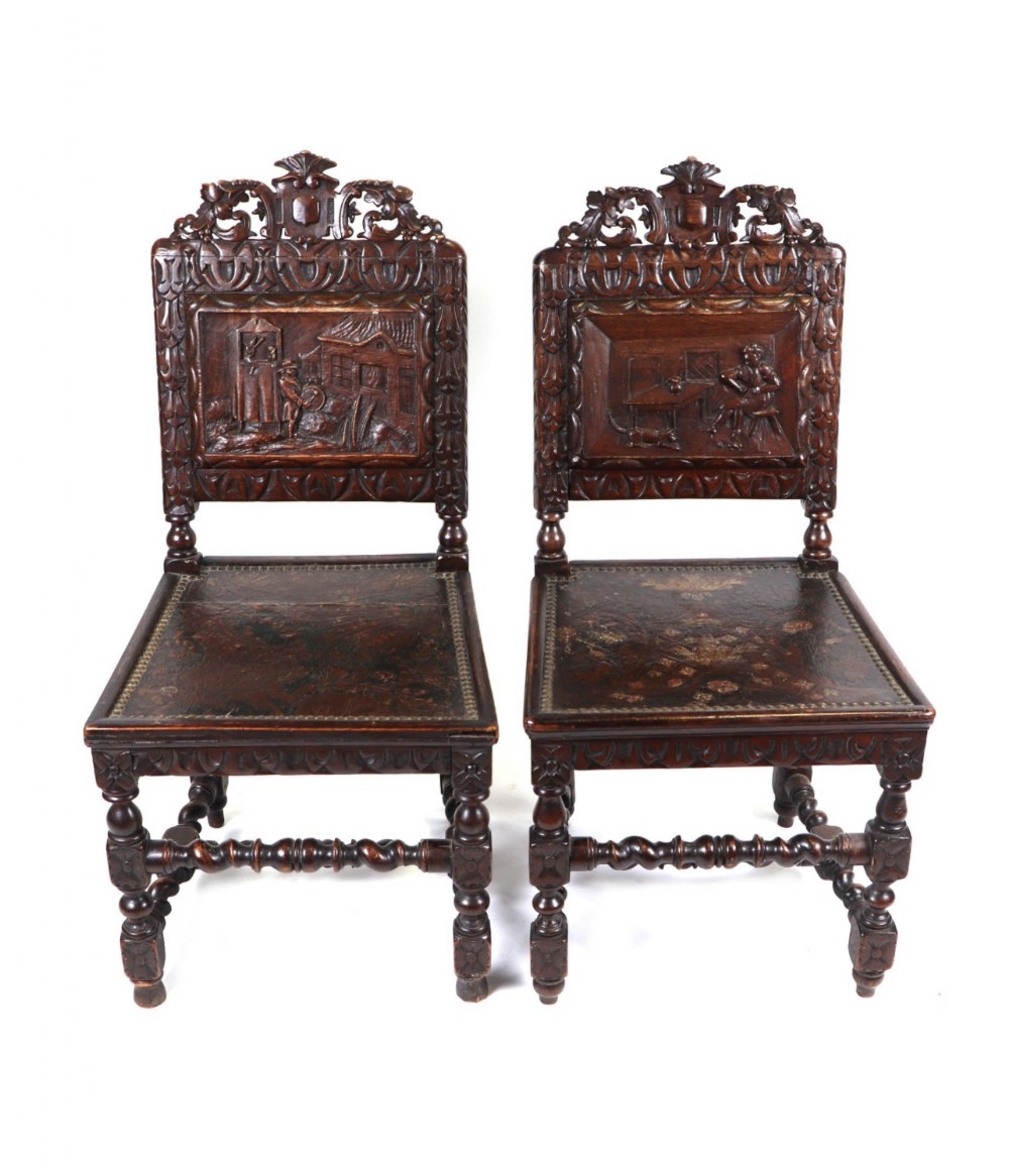 a pair of black forest manner carved chairs with a carved panel depicting a dancing bear show